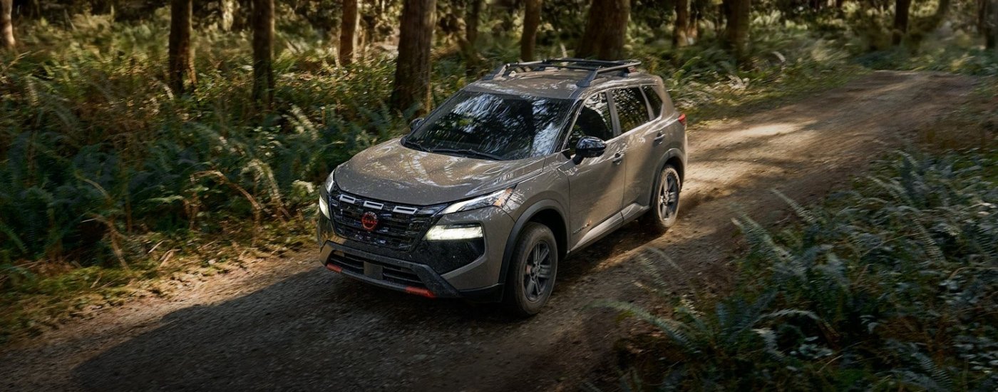 Nissan Rogue Rock Creek 2026 color café conduciendo por un sendero