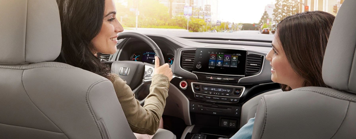 Mother and daughter smiling in the front seats of a 2021 Honda Pilot Elite
