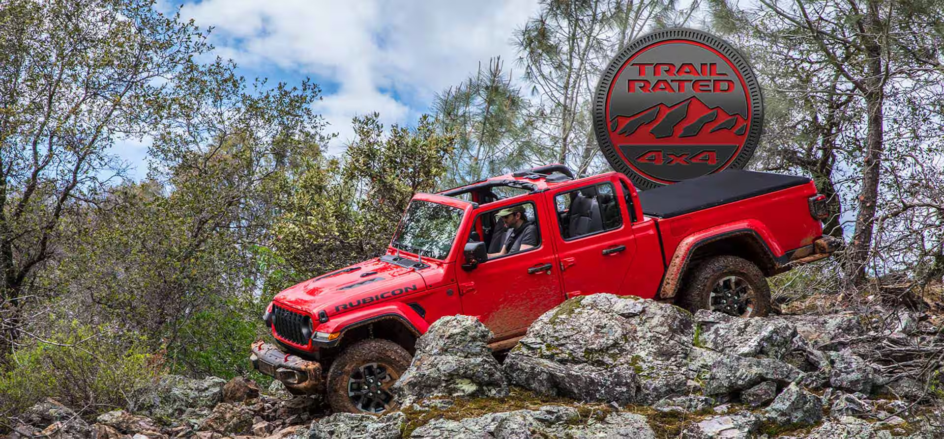 a red jeep gladiator driving over a rocky terrain