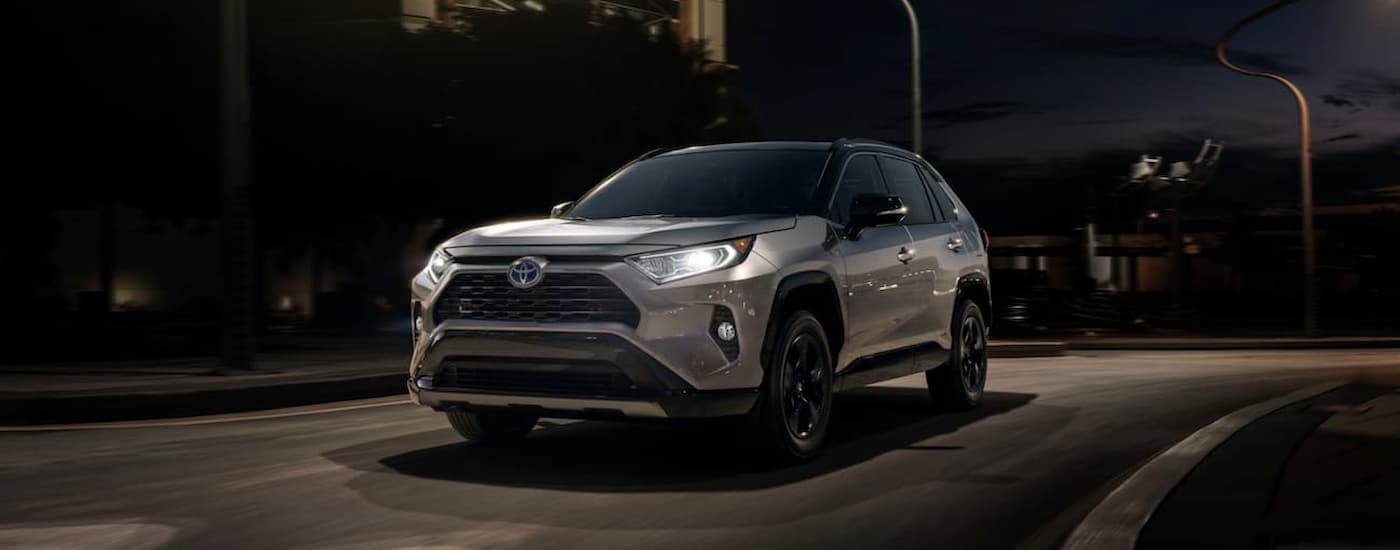 A silver 2020 Toyota RAV4 is shown driving on street at night after viewing used SUVs for sale.