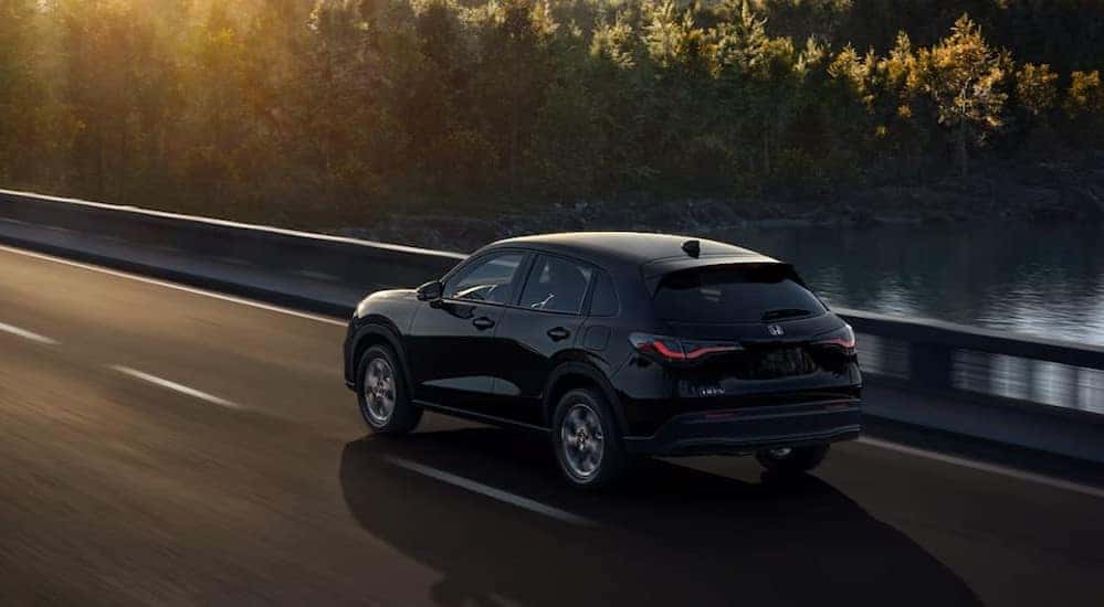 A black 2025 Honda HR-V LX is shown driving on a bridge.