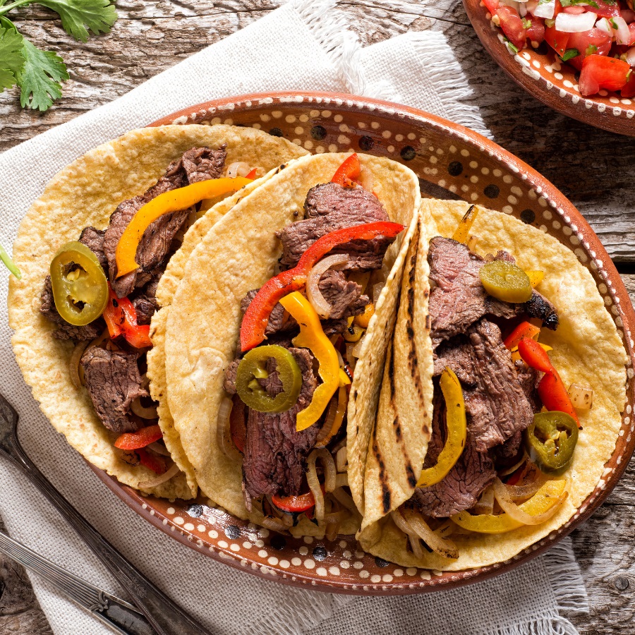 steak fajitas on corn tortillas, topped with bell peppers, onions, and jalepeños