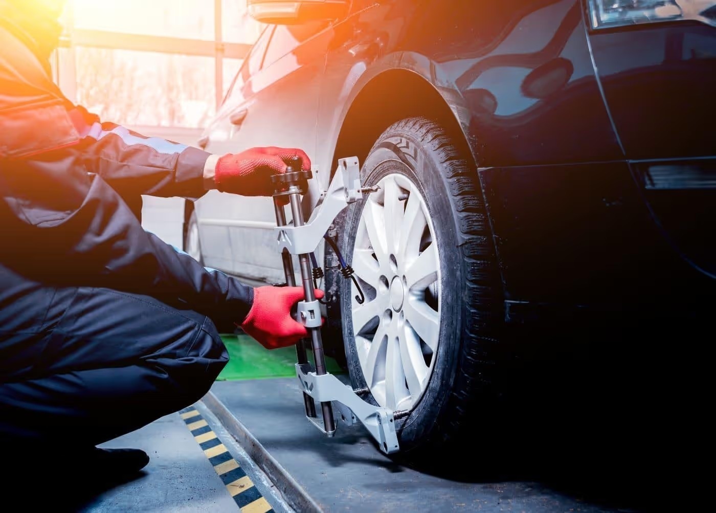 Technician attaching wheel alignment equipment to a car's front wheel