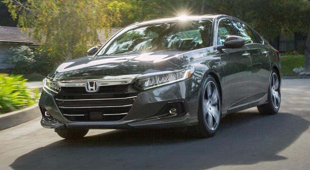 A grey 2021 Honda Accord Hybrid Touring is shown from the front at an angle while driving.