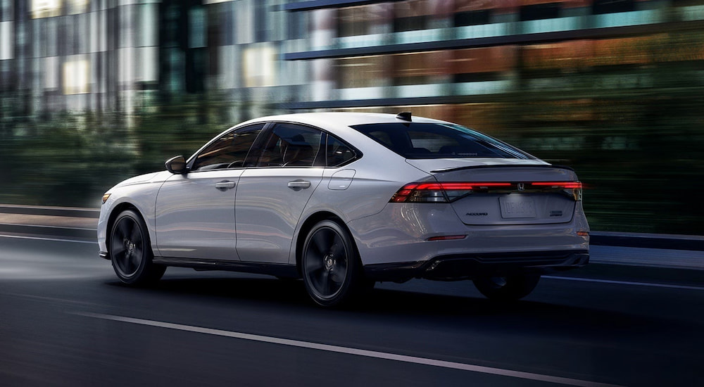 Rear of a white 2026 Honda Accord driving down an open road.
