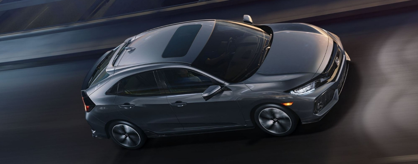 Gray 2020 Honda Civic Hatchback Sport Touring driving on a highway at dusk