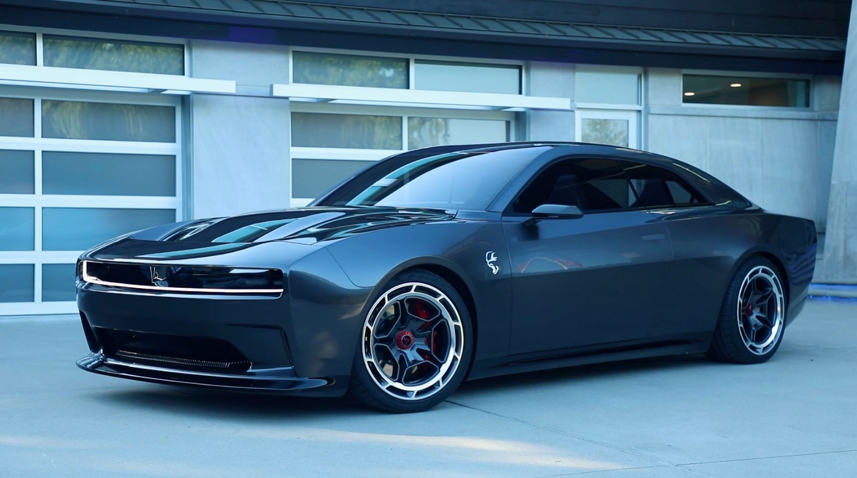 black 2024 Dodge Charger EV parked on a driveway in front of a garage