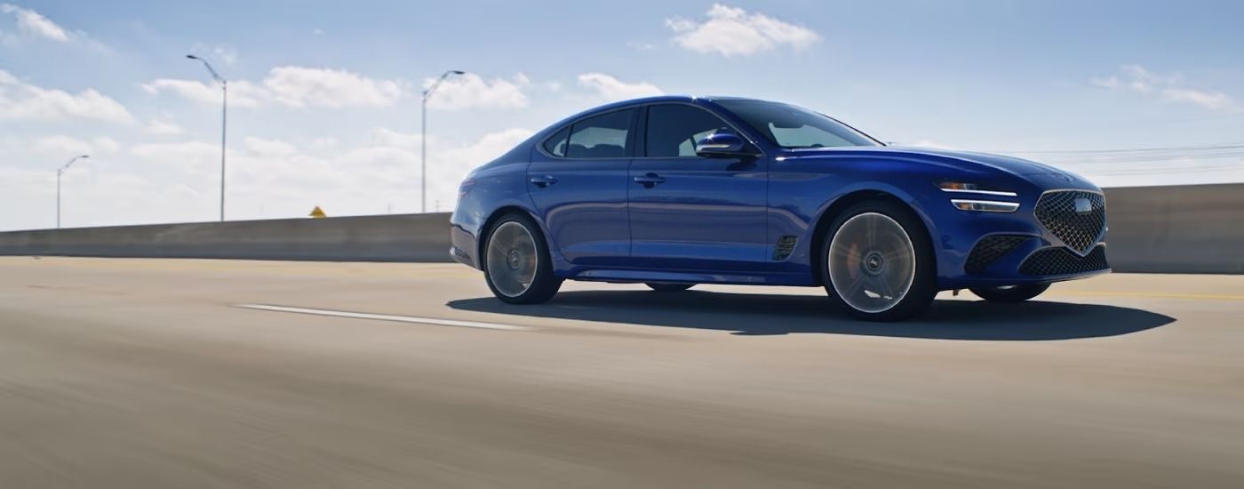 Blue 2025 Genesis G70 driving to a Genesis dealer