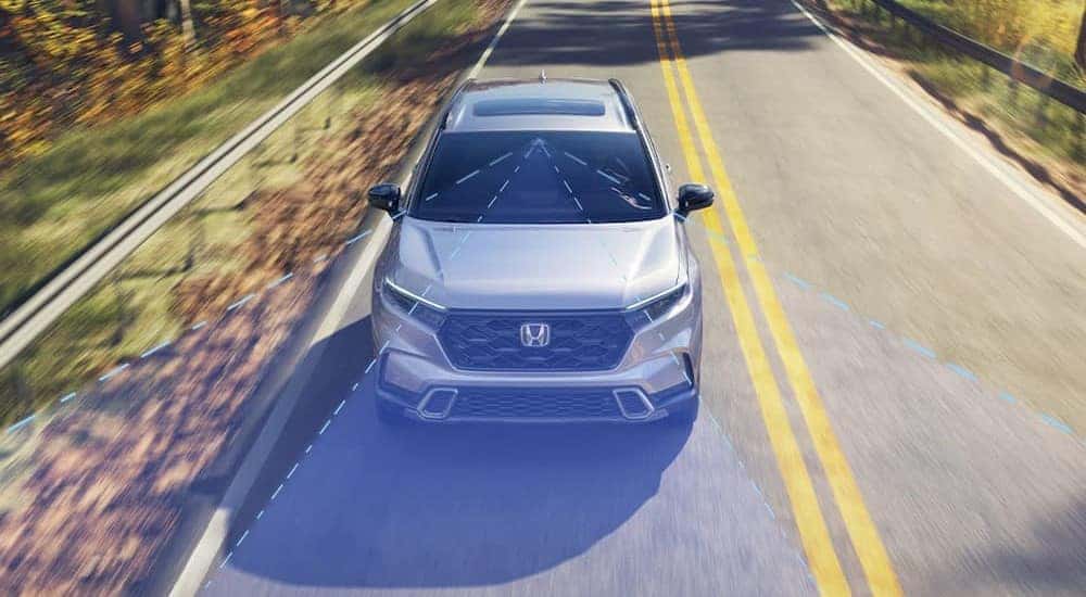 A silver 2023 Honda CRV is shown displaying the Road Departure Mitigation System.