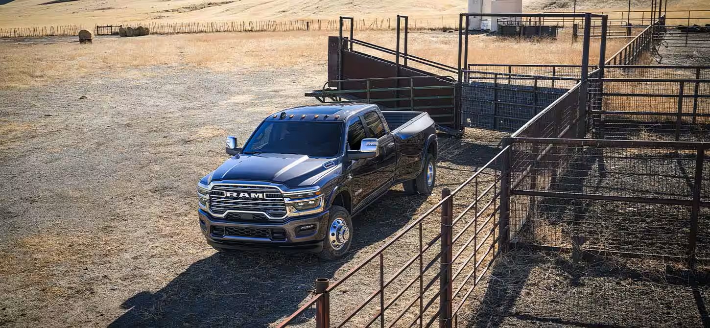A black ram truck sitting parked in a field.