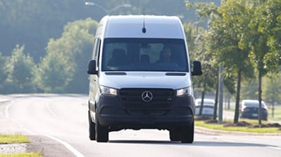 Mercedes-Benz Sprinter van driving down a road