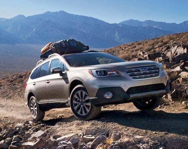 Silver Subaru Outback with a roof box in rocky mountains