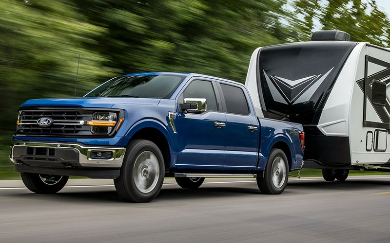 image of black ford f-150 towing trailer with construction equipment