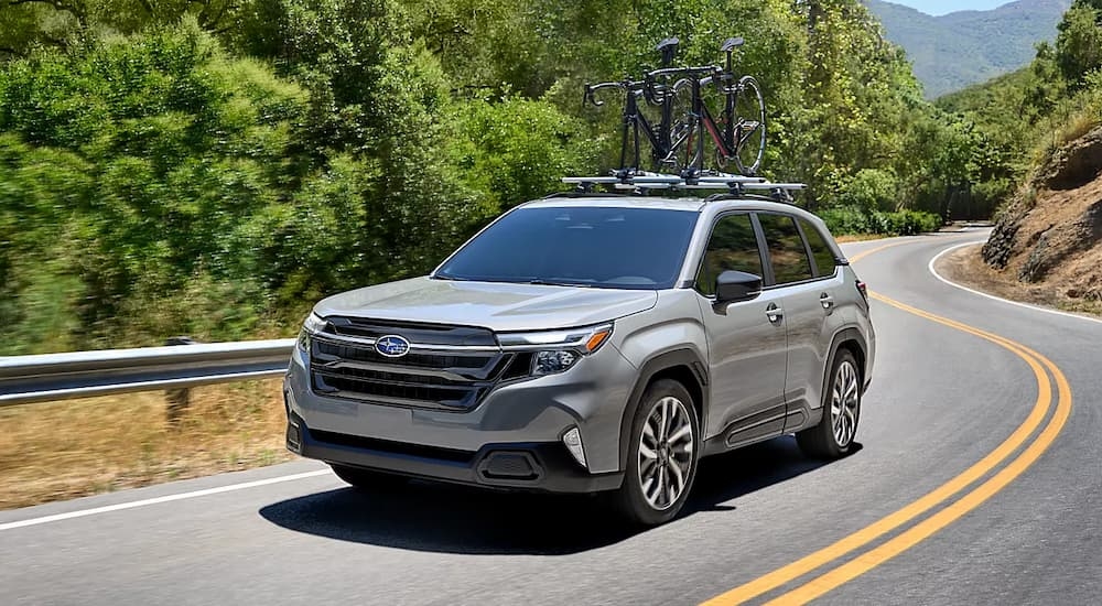 Grey 2026 Subaru Forester driving down a winding road.
