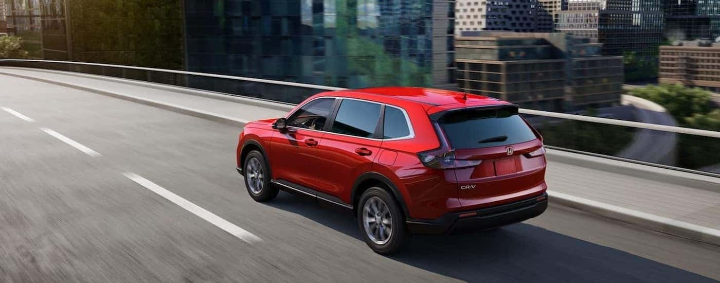 A red 2024 Honda CR-V is shown driving on a bridge.