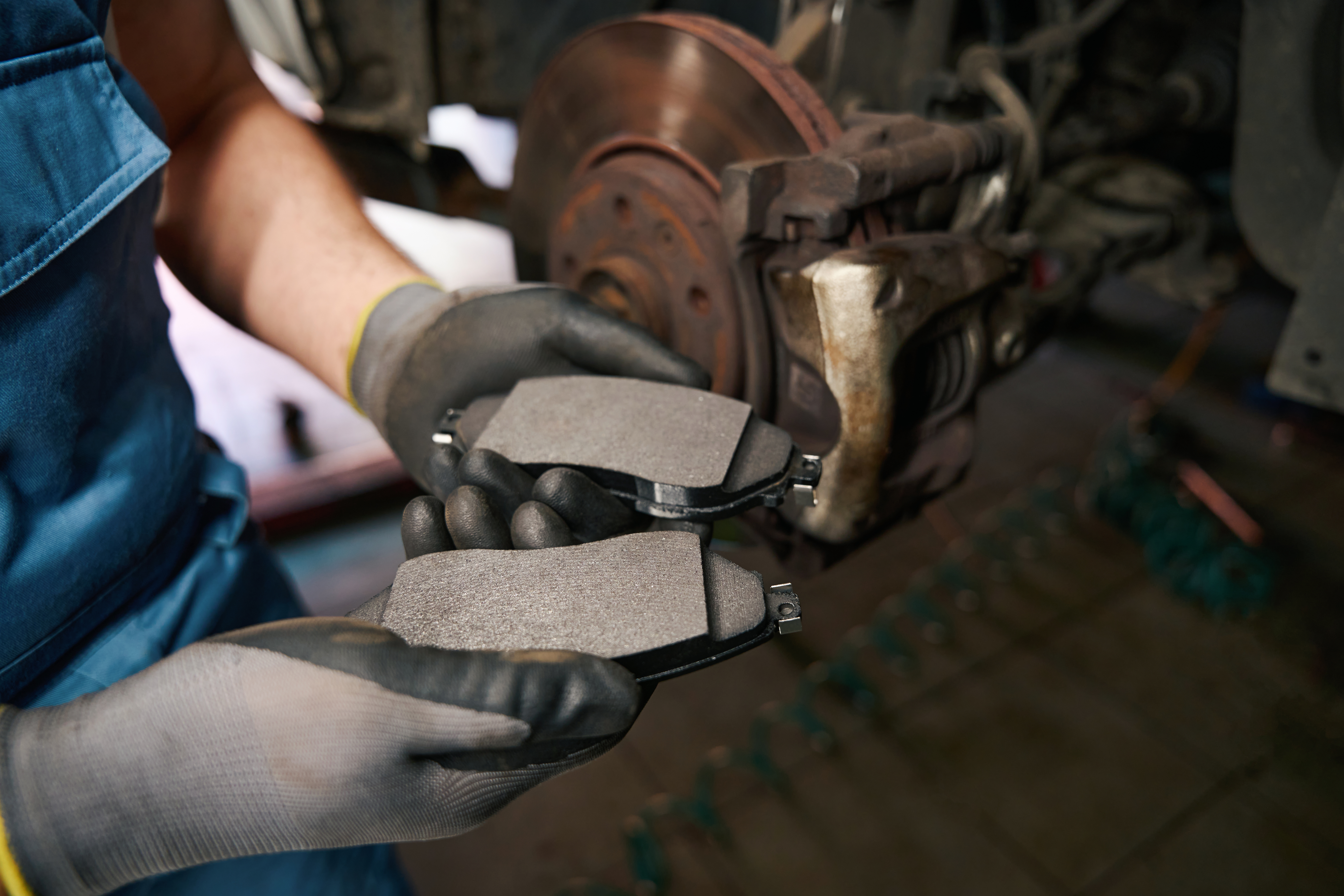 Professional automotive technician replacing car brake pads