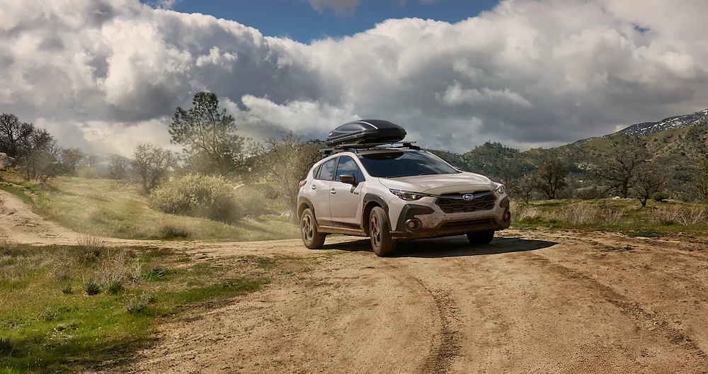 A beige 2026 Subaru Crosstrek driving down a dirt road