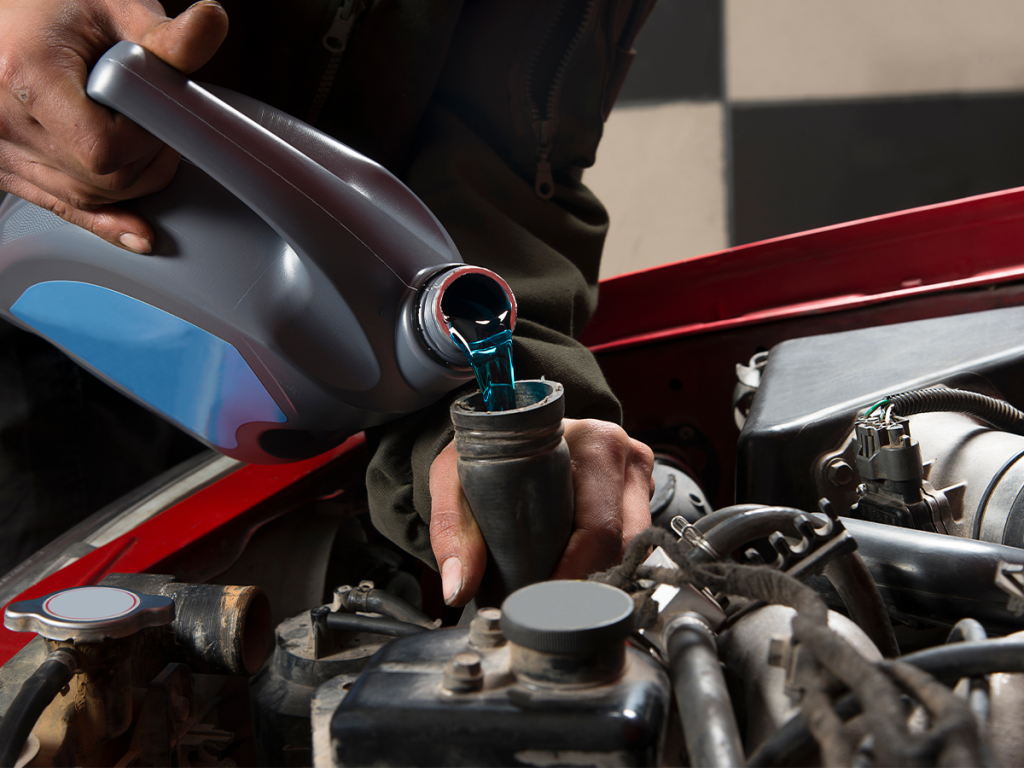 A service technician pours fluid into a car's engine.