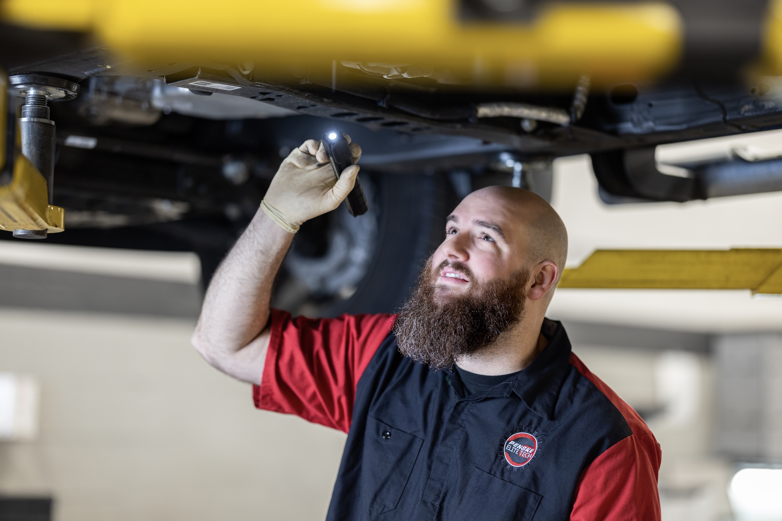 Service Technician examining carriage of car with flashlight