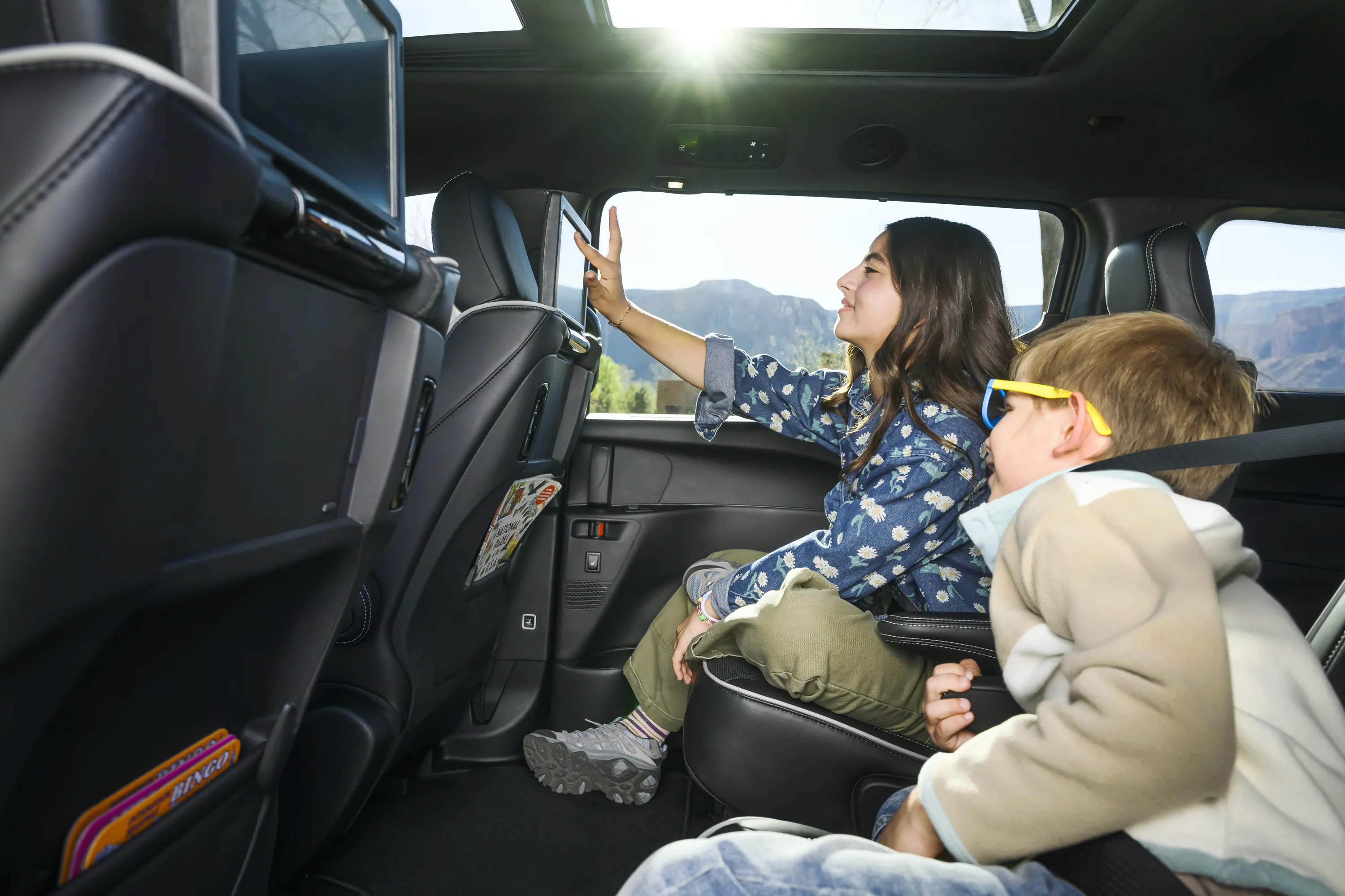 Children in the rear seats of a 2027 Chrysler Pacifica Limited AWD using the available Uconnect Theater Group entertainment screens