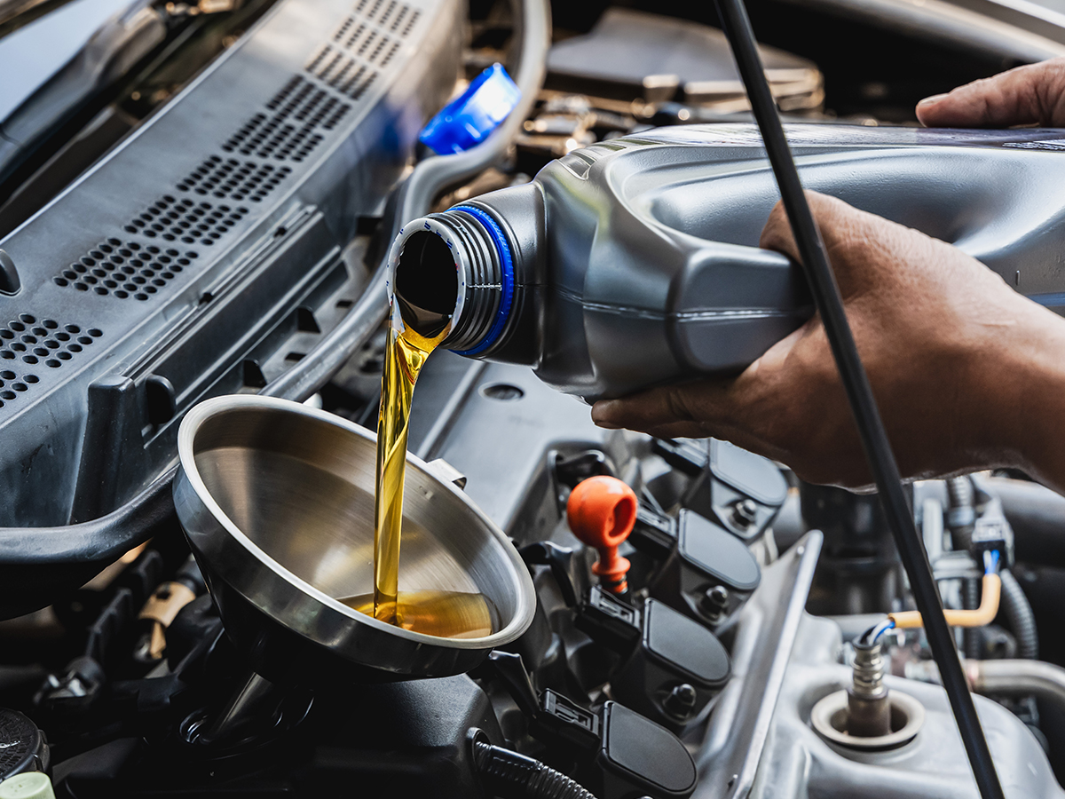 Mechanic pouring oil into a car engine