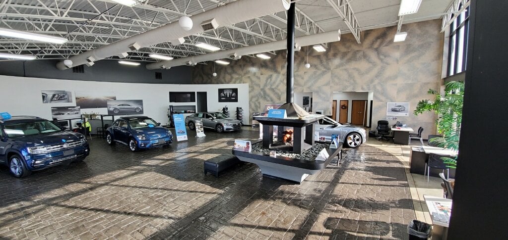 Volkswagen showroom with a blue VW Atlas, Beetle and Arteon around a central fireplace