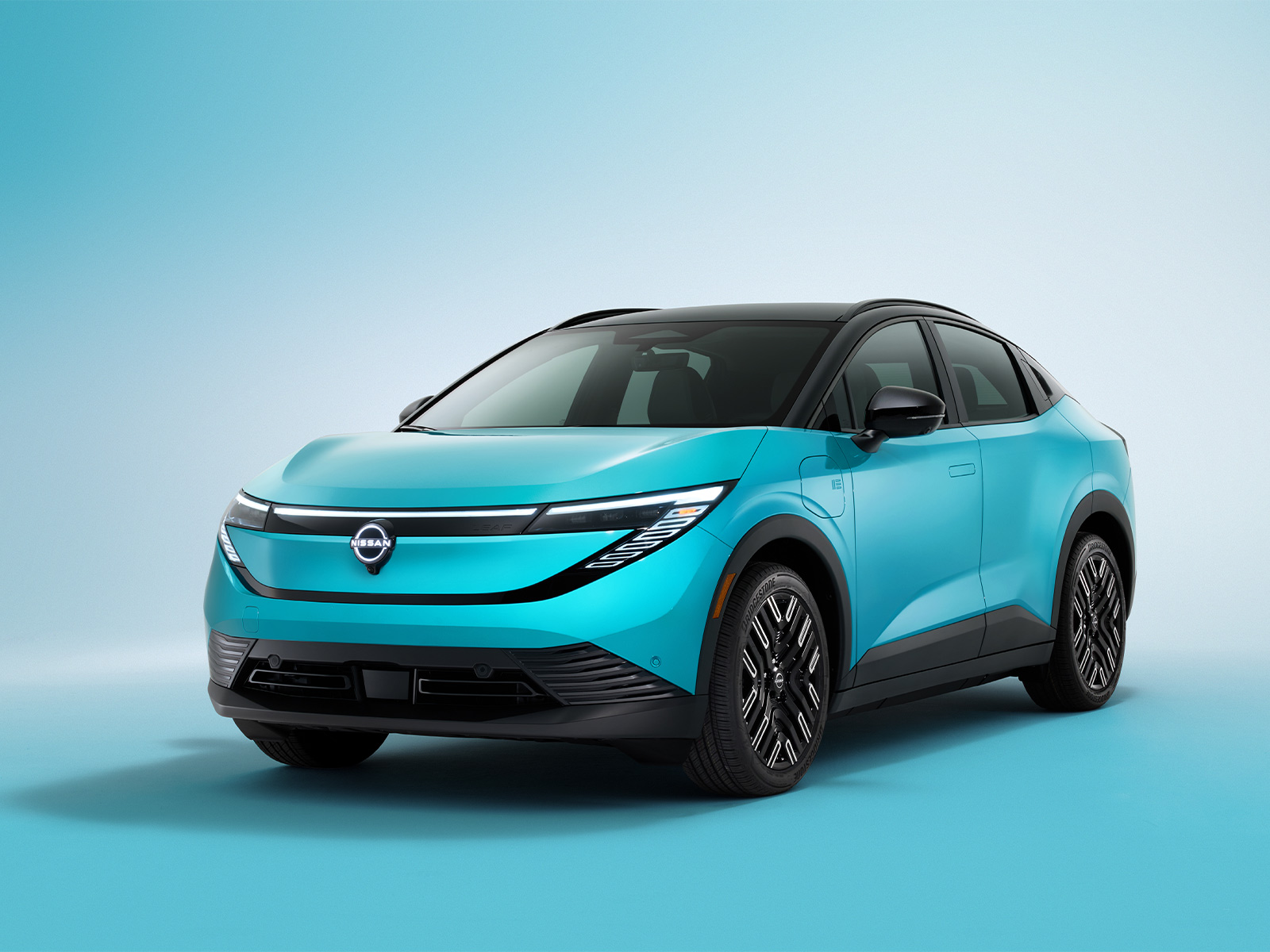Front view of the all-new 2026 Nissan LEAF in a vibrant blue finish, showcasing its sleek aerodynamic design, black roof, and bold LED lighting.