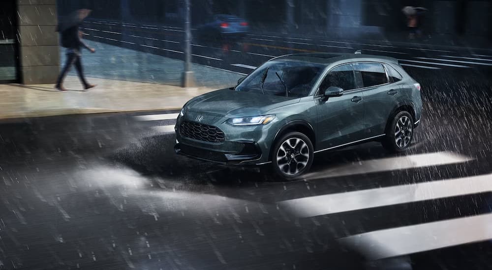 Green 2027 Honda HR-V driving down a rainy road.