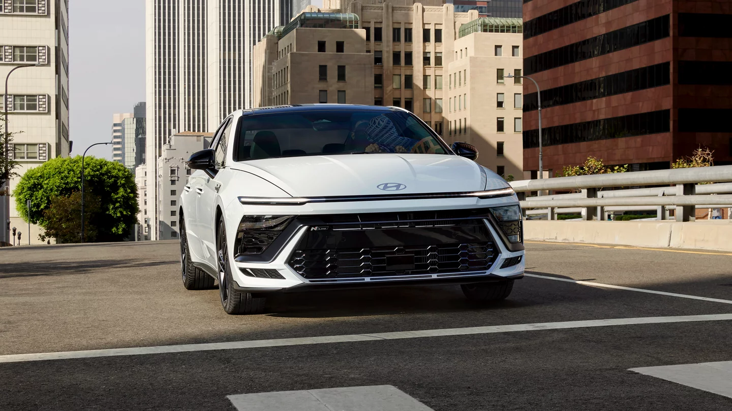 A white Hyundai Sontata sitting in the road.