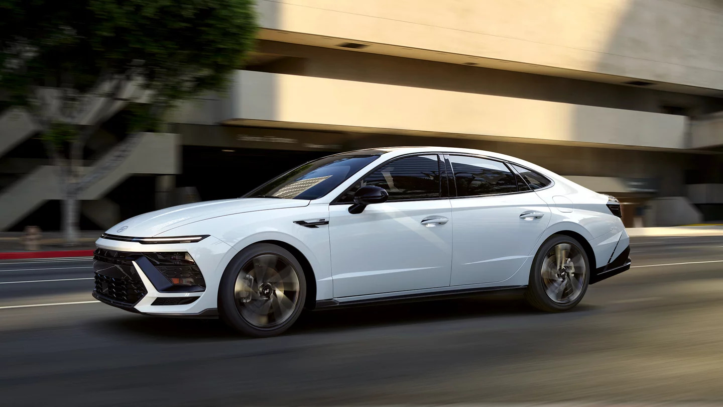 A white Hyundai Sonata driving on a road.