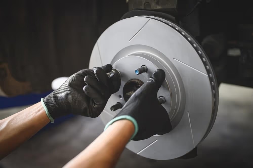 Technician’s gloved hands working on a brake rotor