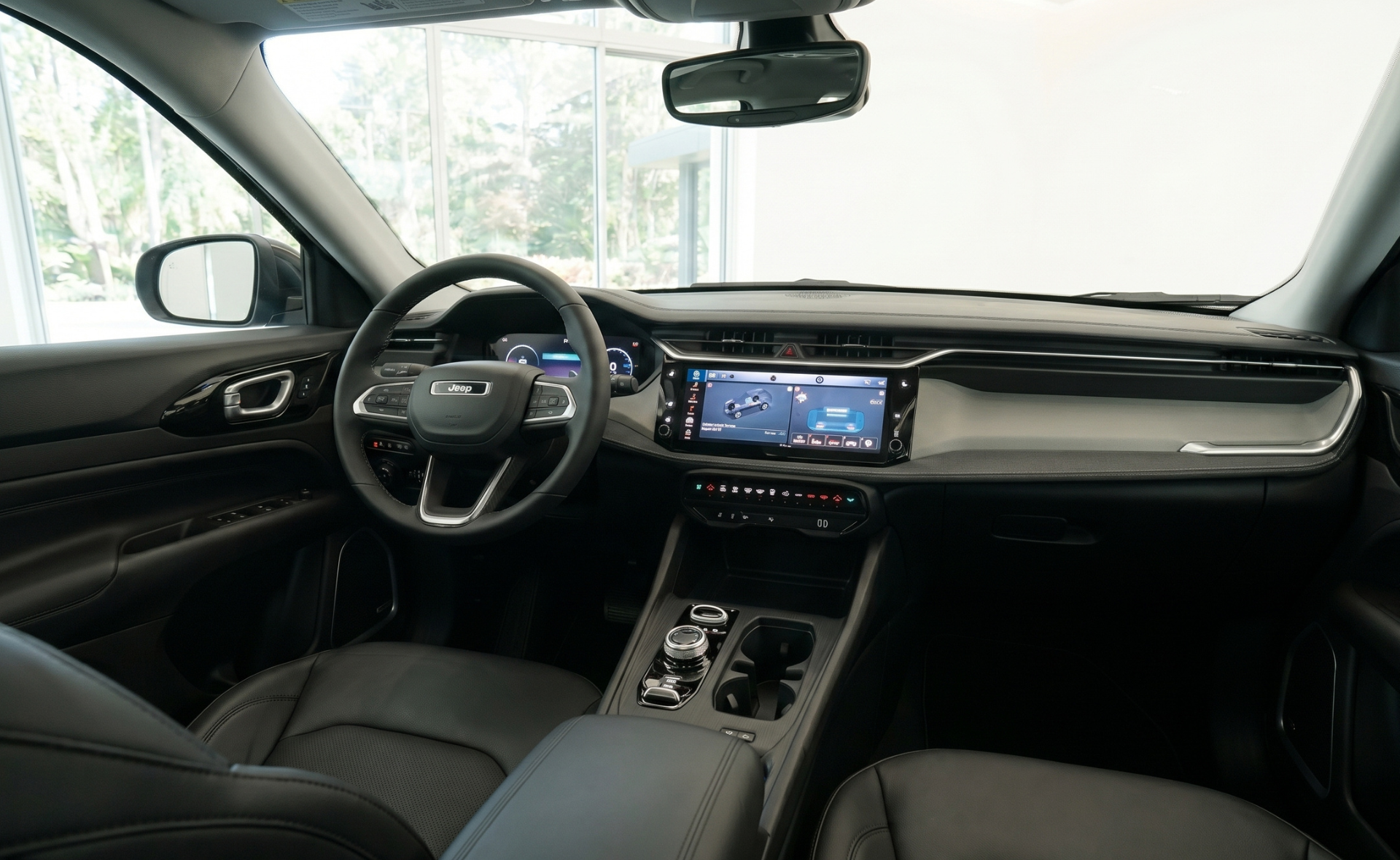 The modern black leather interior and dashboard of a Jeep Compass SUV, showcasing the Uconnect touchscreen infotainment system, digital driver instrument cluster, and premium center console layout.