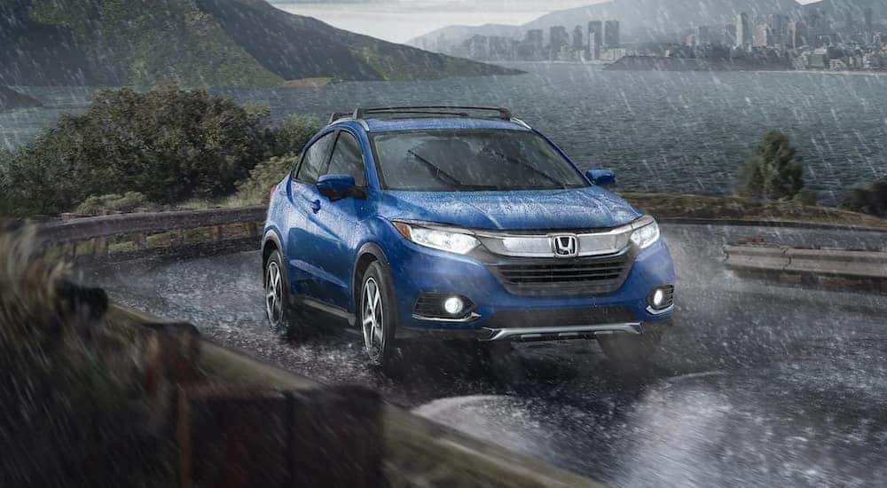 A blue 2021 Honda HR-V EX-L is shown driving in the rain after leaving a car dealer in Rochester.