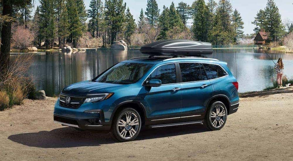Blue 2021 Honda Pilot parked on a lakeshore.