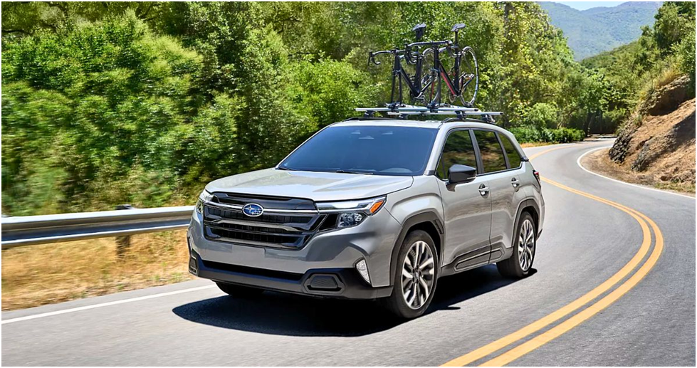 Silver 2025 Subaru Forester with a roof bike rack on a winding forest road