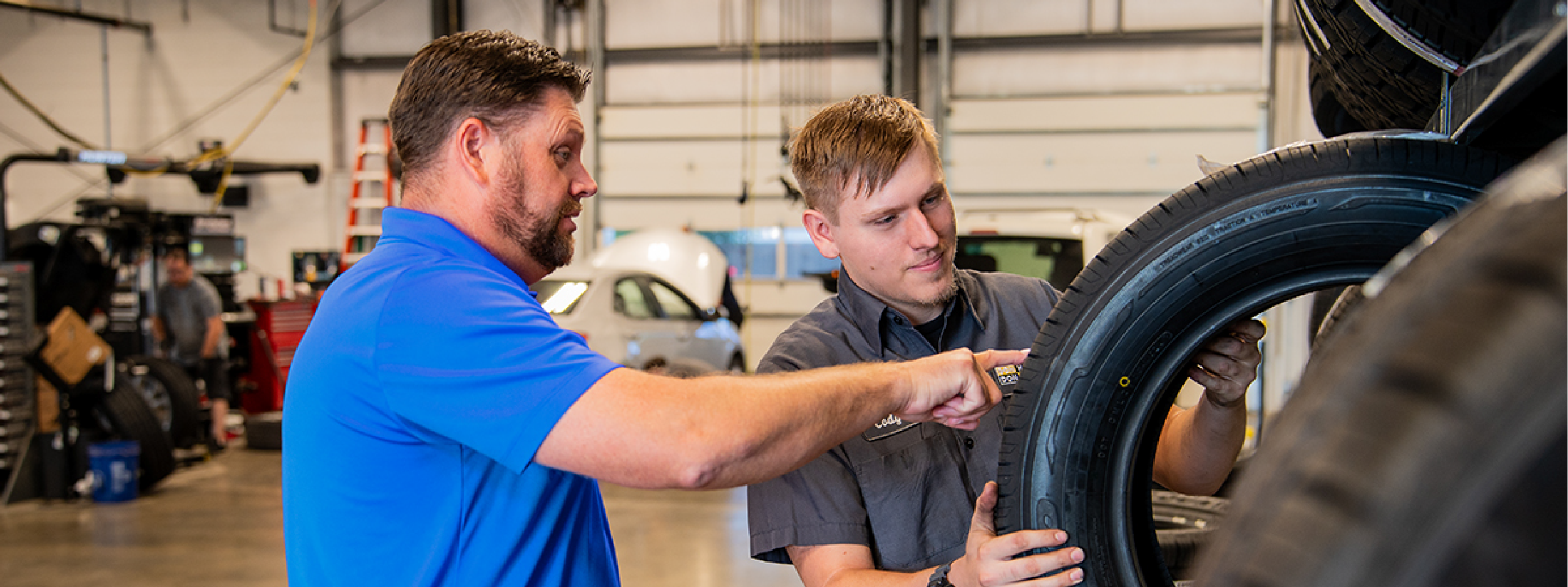 Service Manager and Automotive Technician looking at tire tread
