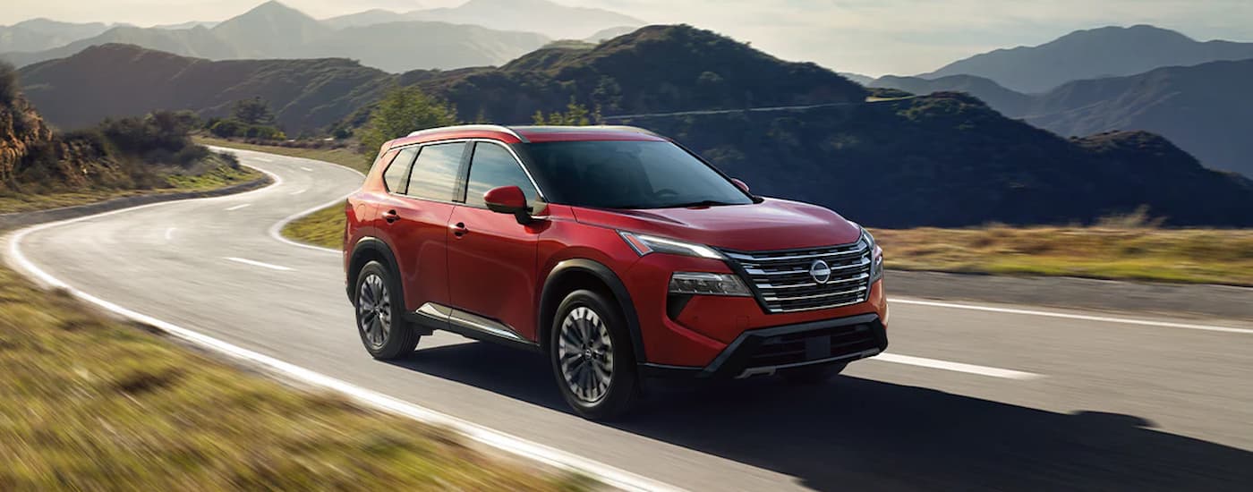 Red 2026 Nissan Rogue driving on a winding road