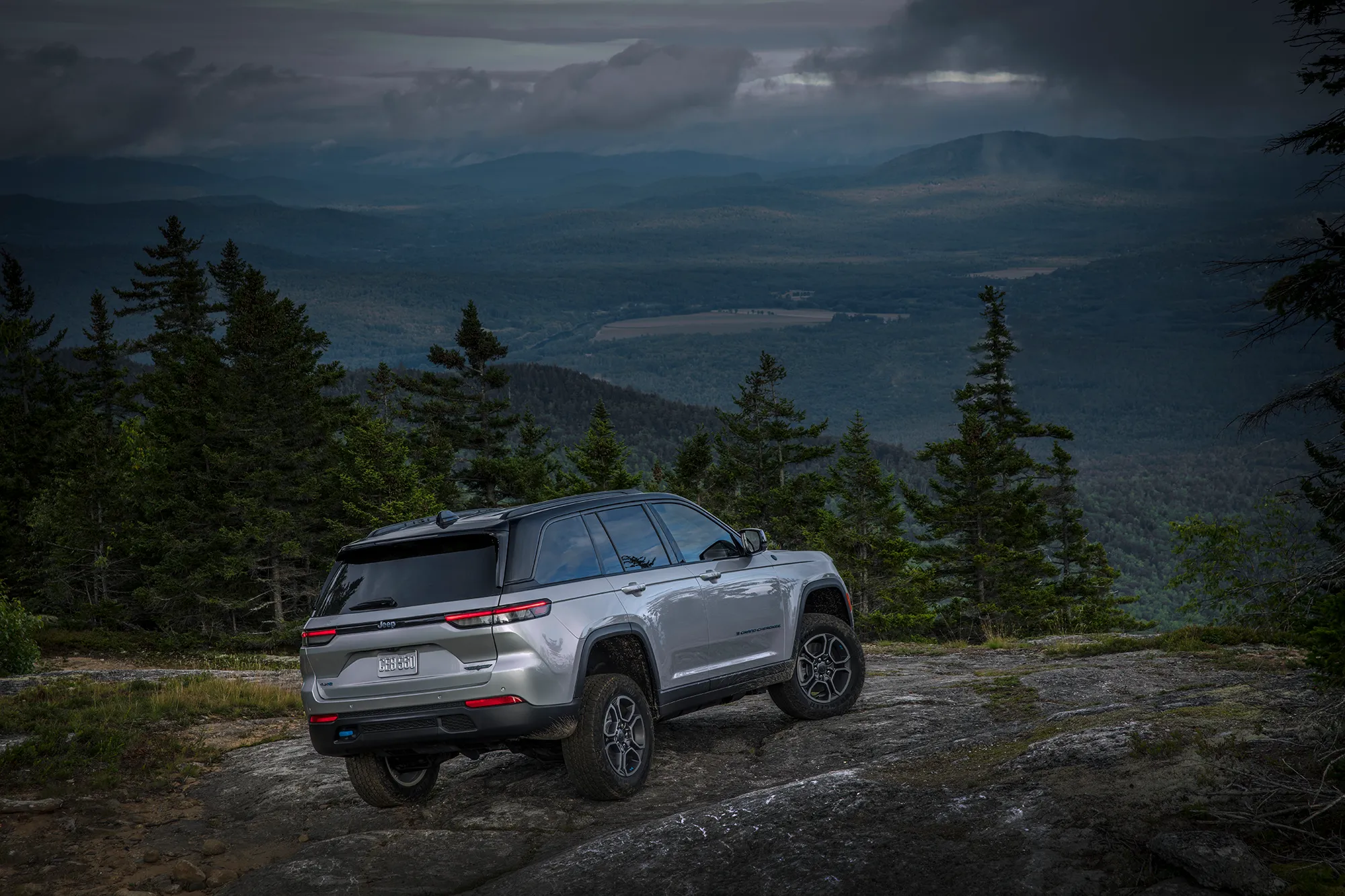 Gray Jeep Grand Cherokee on a rocky trail in a forest at night