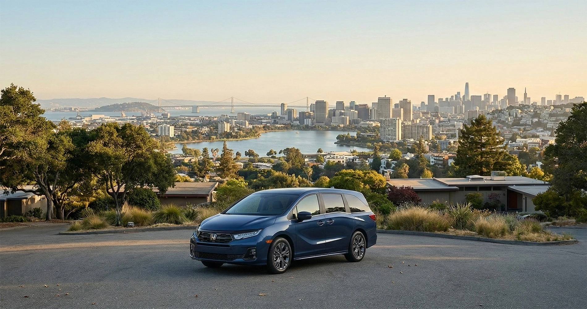 Blue Honda Odyssey minivan parked on a scenic overlook with the Oakland skyline and Lake Merritt in the background