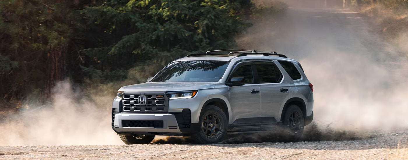 Silver 2026 Honda Pilot kicking up dust down a gravel road