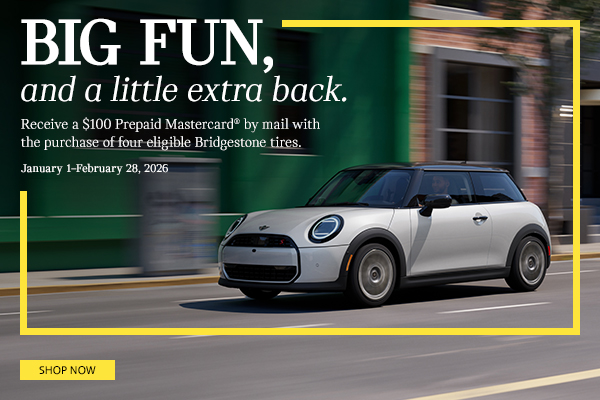 White MINI 2 Door driving down the street.