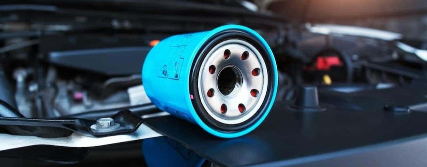 A blue oil filter is shown near the engine bay of a vehicle.