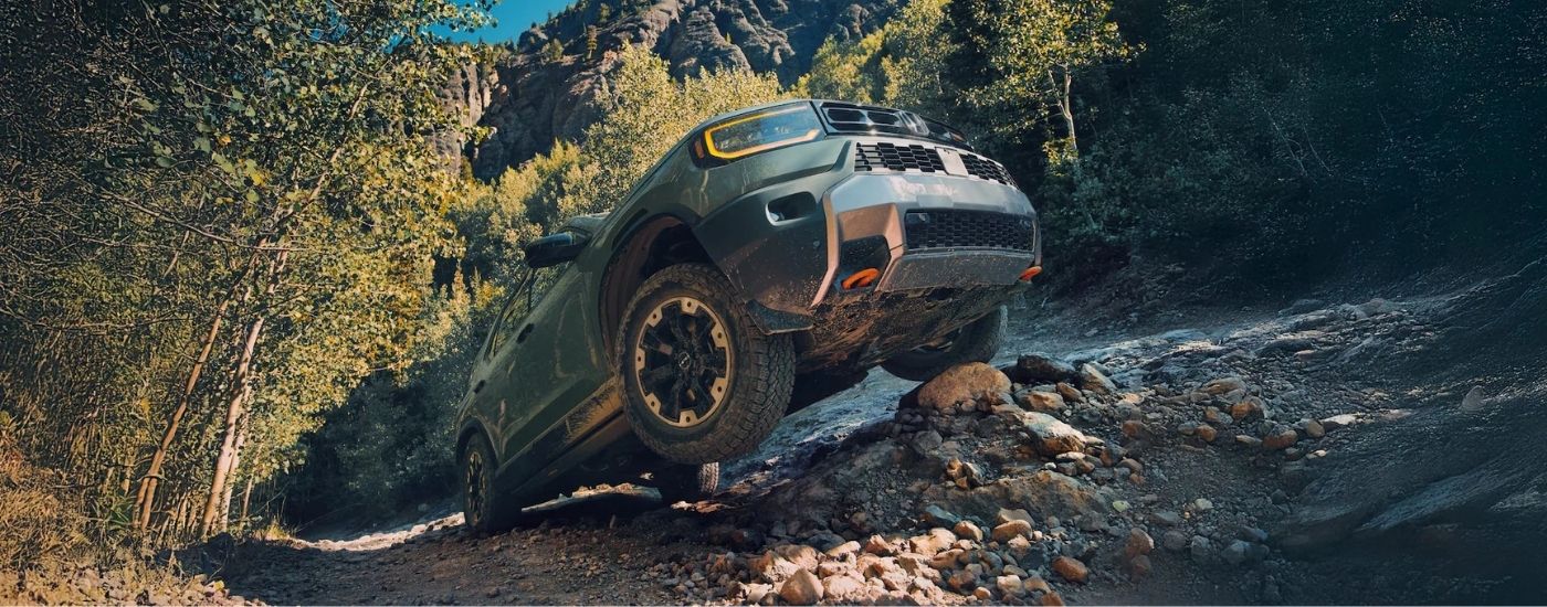 A green 2026 Honda Passport TrailSport crawling up rocks.