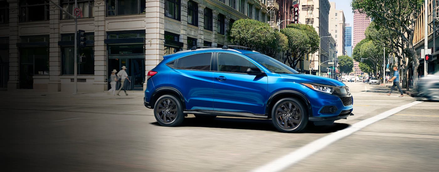 A blue 2021 Honda HR-V is driving on a city street after leaving an Irondequoit Honda Dealer.
