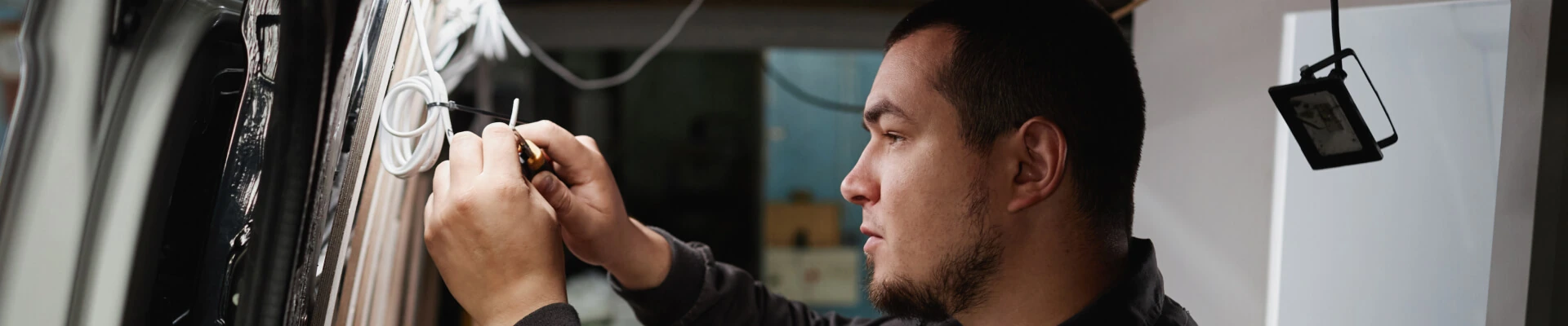Side profile view of a technician installing electrical wiring inside an RV during service.