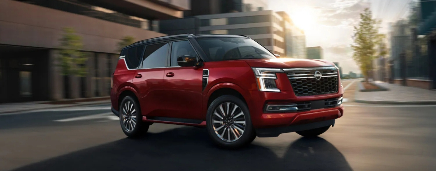 Red 2026 Nissan Armada Platinum driving through an intersection