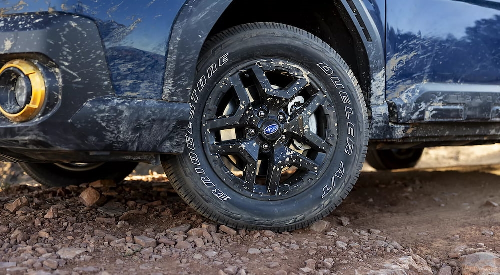 Close-up on the wheels of a dark blue 2026 Subaru Outback parked off-road.