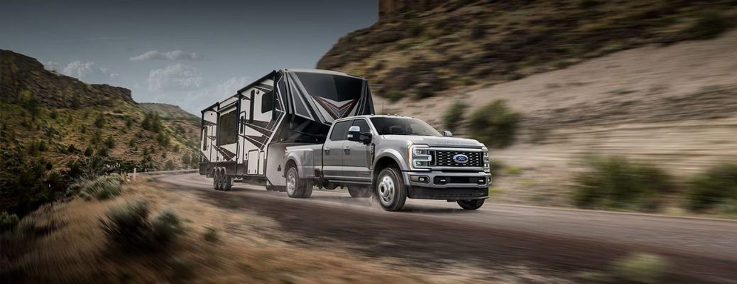 2026 Ford F-350 Super Duty dual-rear-wheel Crew Cab towing a 5th-wheel camper on a canyon road