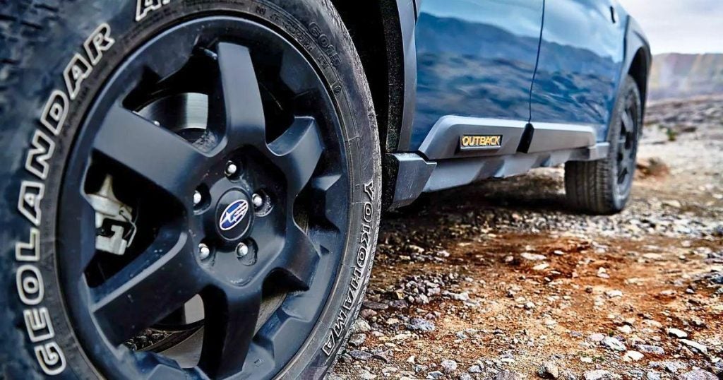 Close-up of a Subaru Outback Wilderness wheel with a Yokohama GEOLANDAR all-terrain tire on rocky ground