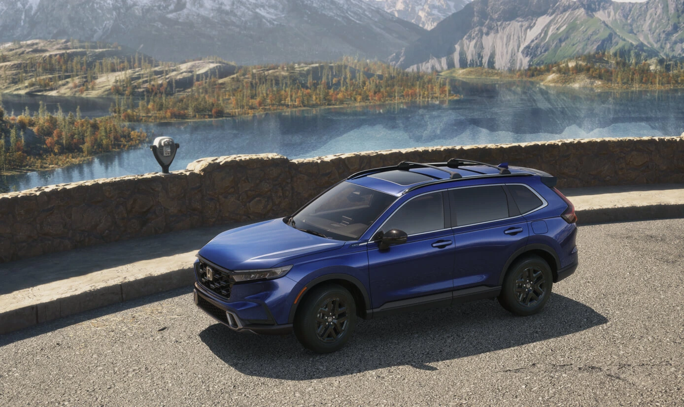High-angle front three-quarter view of a dark blue Honda CR-V Sport Hybrid at a lake overlook.